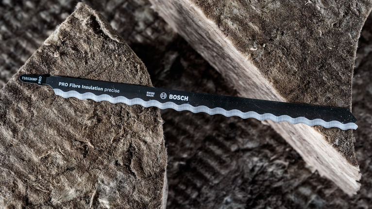 두꺼운 섬유 단열재 시트 위에 놓인 톱니 모양의 톱날.