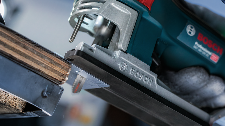 안전 장비를 착용한 사람이 전동 톱을 사용하여 나무를 자르고 있습니다.