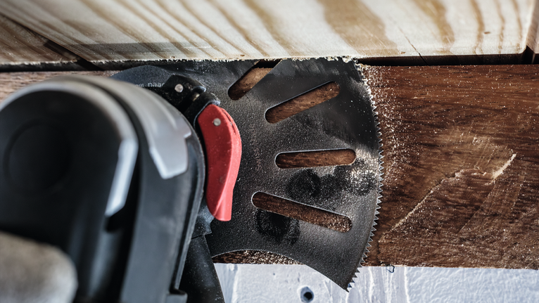 판자 근처의 나무를 자르는 진동식 멀티툴입니다.