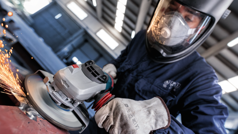 안전 장비를 착용한 사람이 금속을 갈아서 불꽃이 튀는 경우.