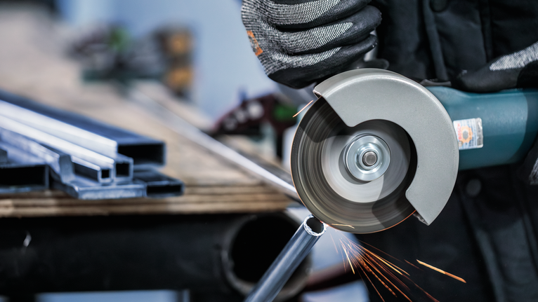 PRO Stainless Steel and Metal 절단석, 105 x 1 x 16mm 안전장비를 착용한 사람이 각도 그라인더로 금속 파이프를 자릅니다.