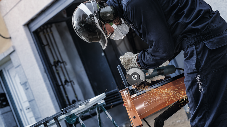 안전 장비를 착용한 사람이 금속을 갈아서 불꽃이 난다.