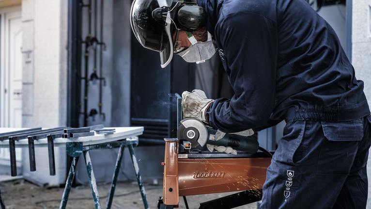 안전 장비를 착용한 사람이 금속을 갈아서 불꽃이 난다.