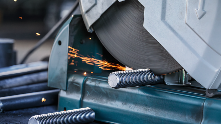 금속 절단 톱이 강철 막대를 자르면서 불꽃이 튀었습니다.