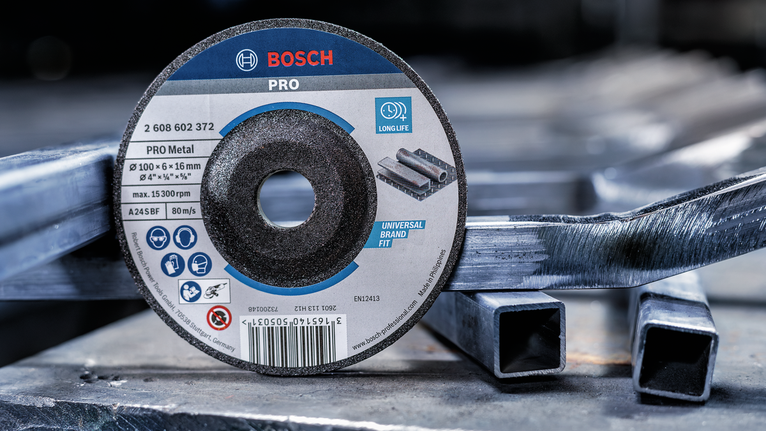 산업 현장에서 쌓인 금속 사각 튜브 위에 놓인 절단 디스크입니다.