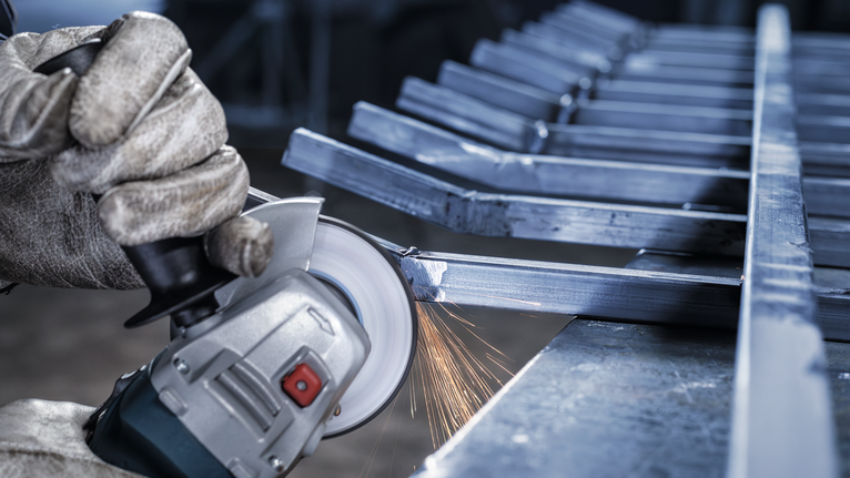 안전 장비를 착용한 사람이 금속을 갈아서 불꽃이 난다.