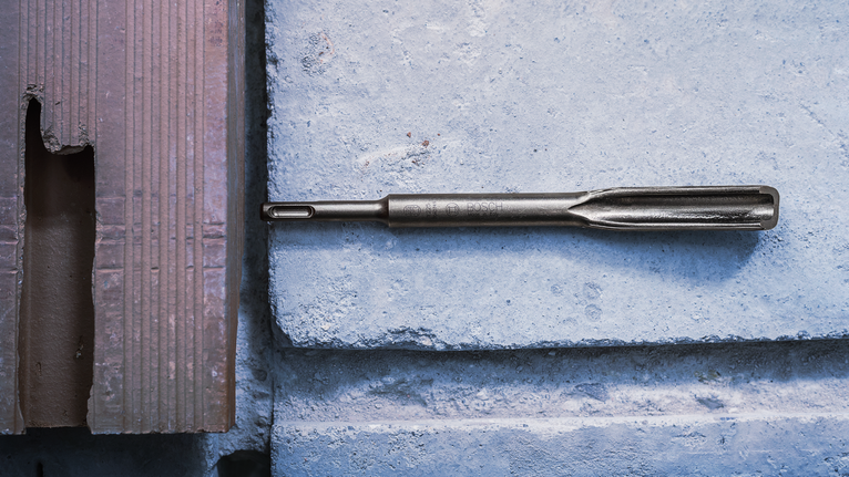 콘크리트 블록 표면에 끌 드릴 비트를 놓았습니다.