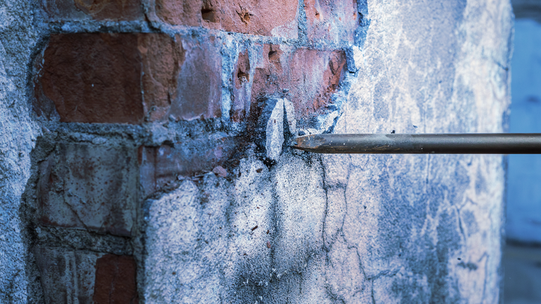 PRO SDS max-4C 포인트 치즐 600mm 드릴 끌로 벽돌 벽의 석고를 부수고 있습니다.