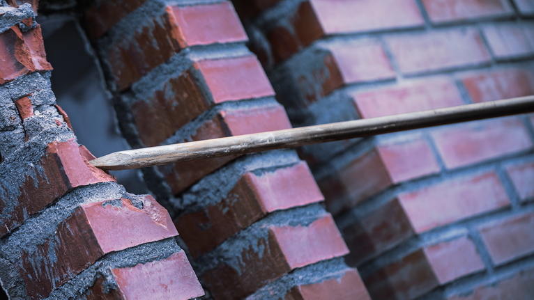 PRO SDS max-4C 포인트 치즐 600mm 날카로운 끌로 벽돌 벽을 부수고 있습니다.