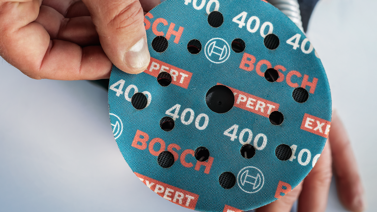 EXPERT O780 포일 샌딩 디스크, 125mm, G60 사람이 둥근 연마 디스크를 도구 위에 올려 놓습니다.