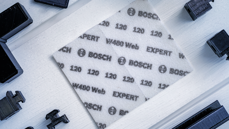 EXPERT W480 Web 1/4 핸드 샌딩 시트, 115 x 140mm, G120 인쇄된 사양이 적힌 흰색 연마 시트를 밝은 색 나무 표면에 놓습니다.