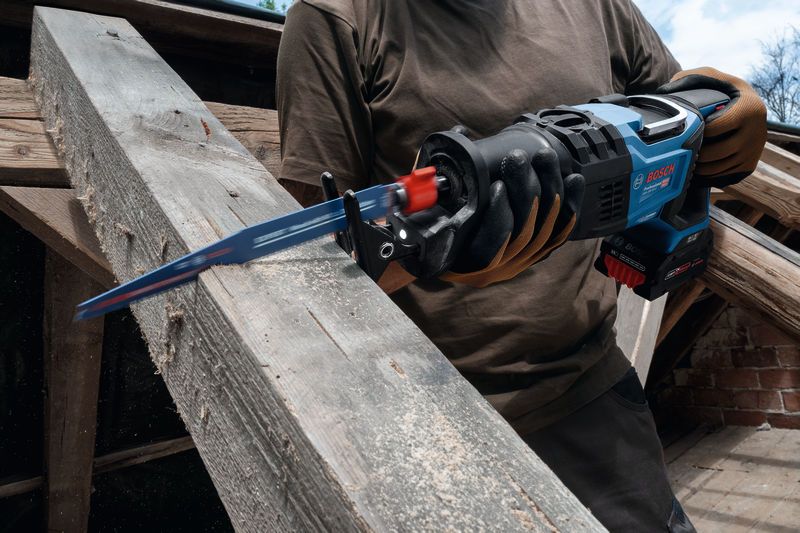 안전 장비를 착용한 사람이 왕복톱을 사용해 나무 들보를 자릅니다.