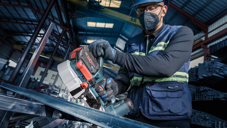 PRO CB2824 Band 톱날, 733mm, 2개 안전 장비를 착용한 사람이 산업 현장에서 휴대용 톱을 이용해 금속을 자르고 있습니다.