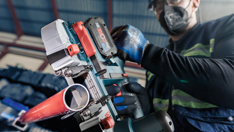PRO CB2824 Band 톱날, 733mm, 2개 안전 장비를 착용한 사람이 무선 전동 공구를 사용하여 금속 파이프를 절단하고 있습니다.