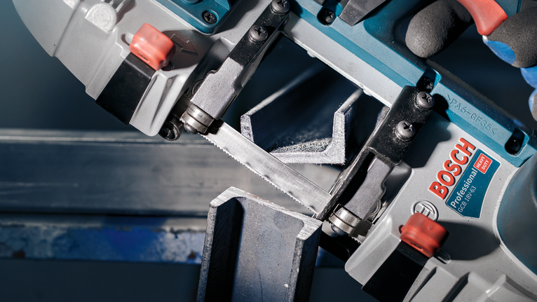 PRO CB2824 Band 톱날, 733mm, 2개 안전 장비를 착용한 사람이 전기톱을 사용하여 금속 빔을 자릅니다.