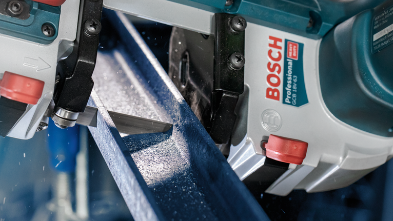 작업장에서 밴드톱으로 금속 빔을 절단하는 모습.