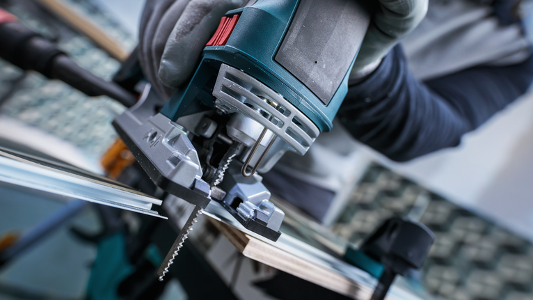 안전 장비를 착용한 사람이 퍼즐을 이용해 나무판을 자르고 있습니다.