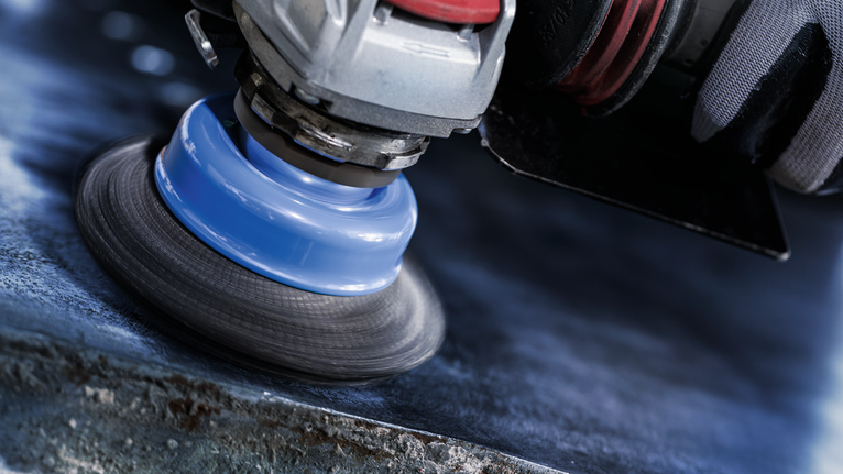 PRO Metal clean X-Lock 컵 브러시, 75 x 0.3mm 안전장비를 착용한 사람이 회전 도구로 금속을 닦고 있습니다.