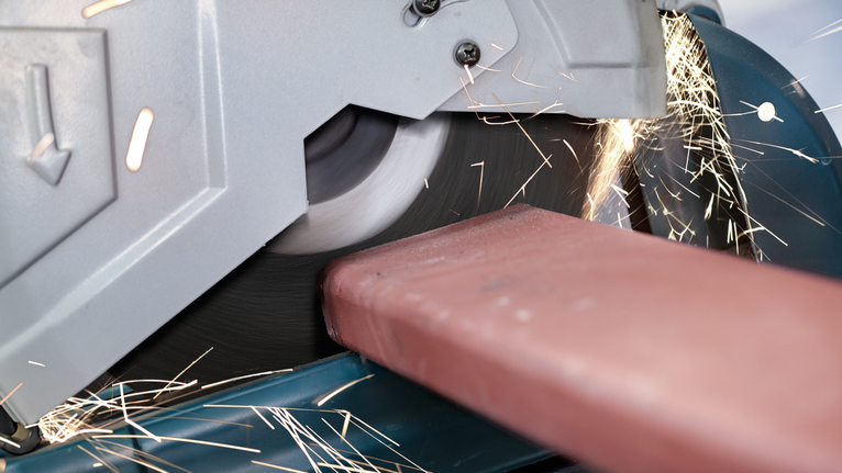 절단 톱으로 금속 빔을 자르면서 불꽃을 냅니다.