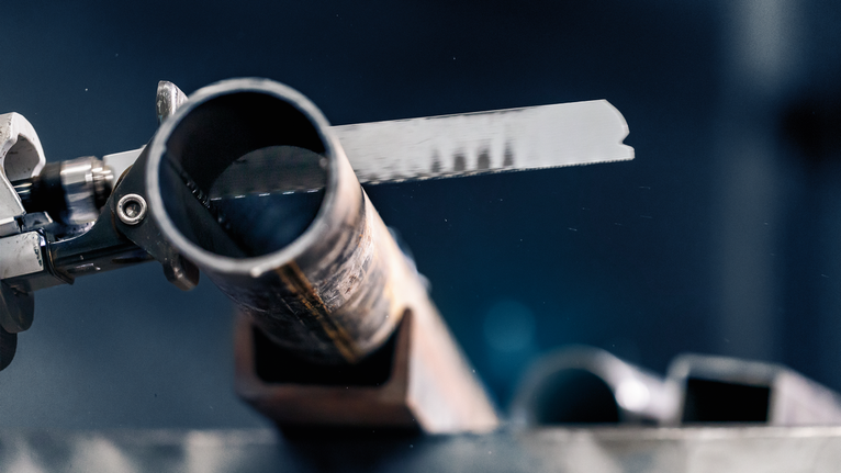 금속 절단 톱날이 강철 파이프를 자르는 모습.