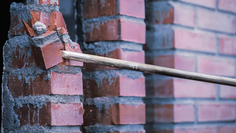 모르타르 벽에서 붉은 벽돌을 부수는 철거 막대.