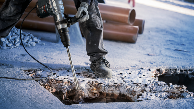 PRO SDS max-5C 플랫 치즐, 25 x 400mm 안전 장비를 착용한 사람이 대형 전동 공구를 이용해 콘크리트 바닥을 부수고 있습니다.