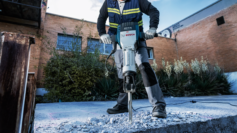 PRO HEX 28-4C 플랫 치즐, 35 x 520mm 안전 장비를 착용한 사람이 야외에서 철거 망치를 이용해 콘크리트를 깨고 있습니다.