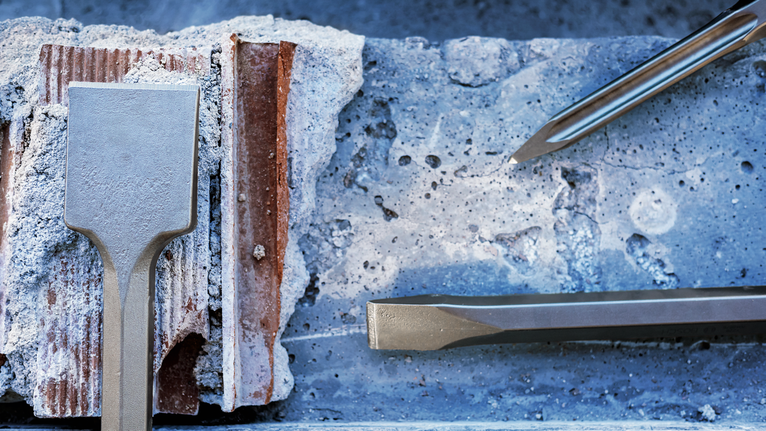 PRO HEX 28-4C 플랫 치즐, 35 x 520mm 건설 현장에서 콘크리트 블록을 끌로 부수는 모습.