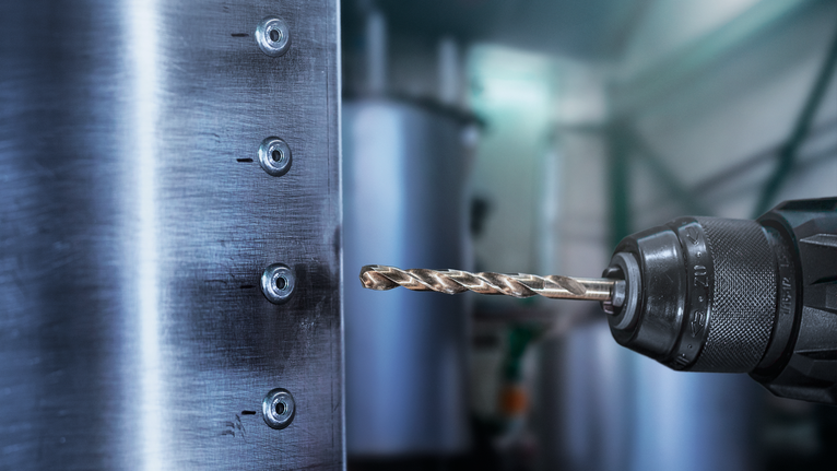 금속 패널에 구멍을 뚫는 전동 드릴.