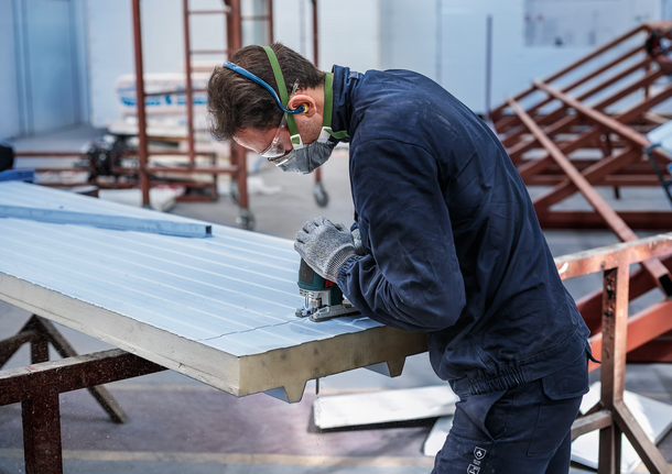 안전 장비를 착용한 사람이 퍼즐을 사용하여 단열 패널에 홈을 파고 있습니다.