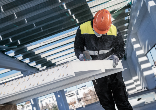 안전 장비를 착용한 사람이 전동 공구를 사용하여 건설용 들보를 자르고 있습니다.