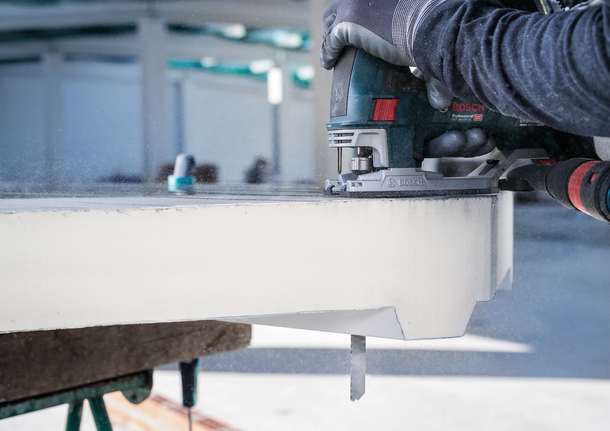 안전 장비를 착용한 사람이 퍼즐을 사용하여 두꺼운 석판을 자릅니다.