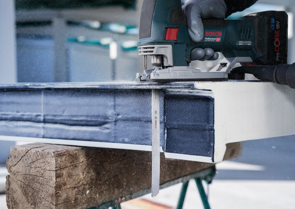 안전 장비를 착용한 사람이 왕복톱을 사용해 금속 막대를 자릅니다.