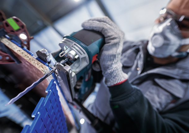 안전장비를 착용한 사람이 퍼즐로 나무판을 자릅니다.