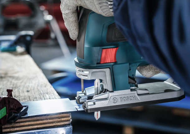 안전 장비를 착용한 사람이 퍼즐을 사용하여 금속판을 자릅니다.