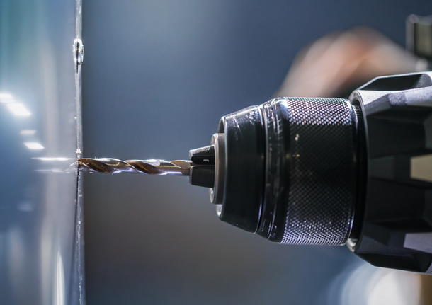 금속 표면에 구멍을 뚫는 전동 드릴.