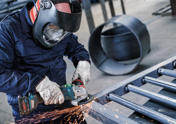 안전 장비를 착용한 사람이 금속을 갈아서 불꽃이 난다.