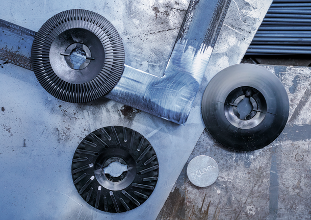 긁힌 금속 표면 위에는 서로 다른 세 개의 분쇄 디스크와 금속 어댑터가 놓여 있습니다.