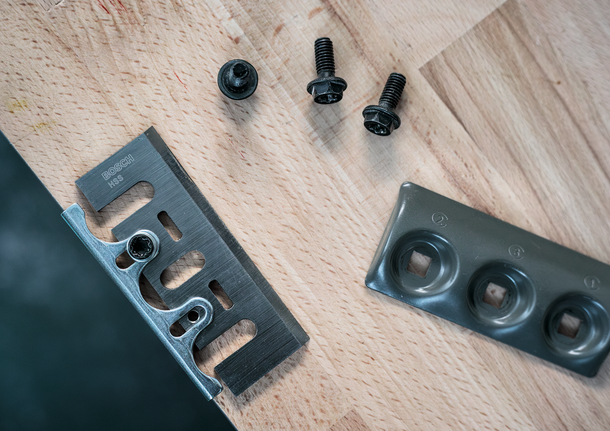 금속 칼날, 고정 나사, 그리고 나무 표면에 배열된 장착판.