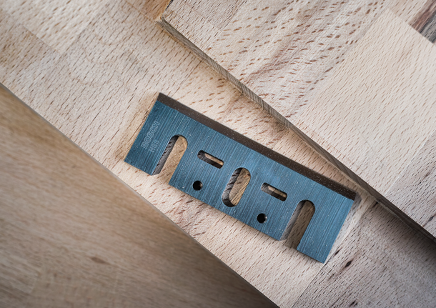 쌓인 나무판 위에 금속 실용 칼날을 올려놓은 모습입니다.