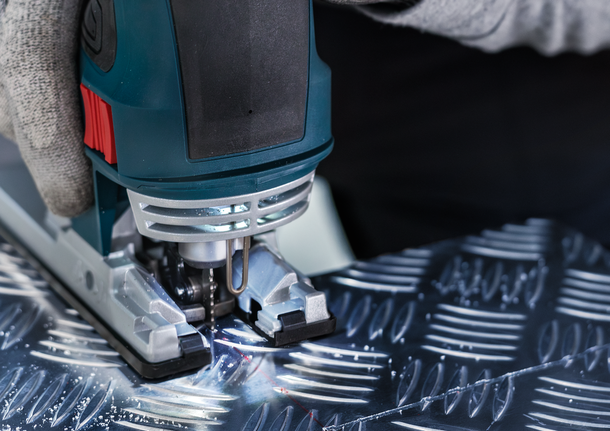 PRO Alu T127D 직쏘날, 100mm, 5개 안전 장비를 착용한 사람이 퍼즐을 사용해 무늬가 있는 금속을 자릅니다.