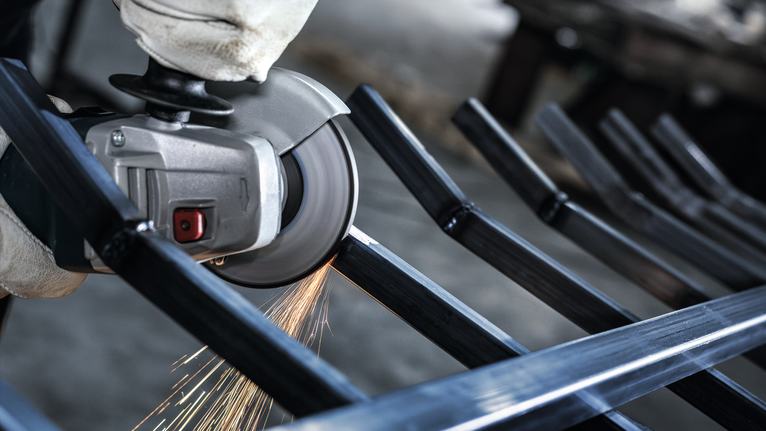 안전 장비를 착용한 사람이 금속 막대를 갈아서 불꽃이 난다.