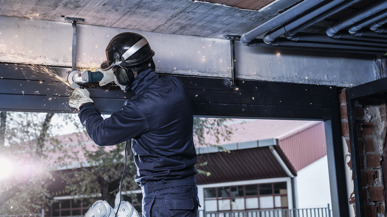 안전 장비를 착용한 사람이 금속 막대를 갈아서 실내에서 불꽃이 튀는 현상.