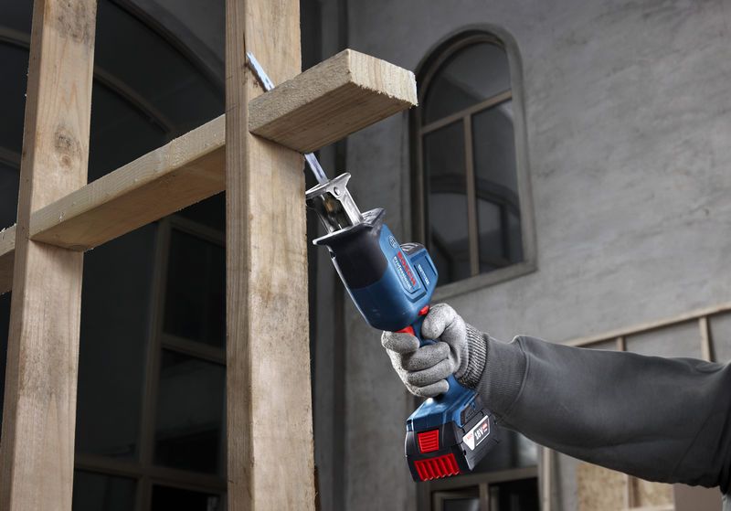 안전 장비를 착용한 사람이 왕복톱을 사용해 나무 들보를 자릅니다.