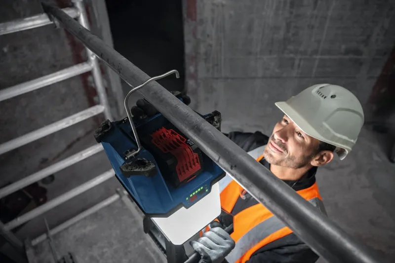 GLA 18VH-7500 안전 장비를 착용한 사람이 무선 작업 현장 조명을 금속 파이프에 설치하고 있습니다.