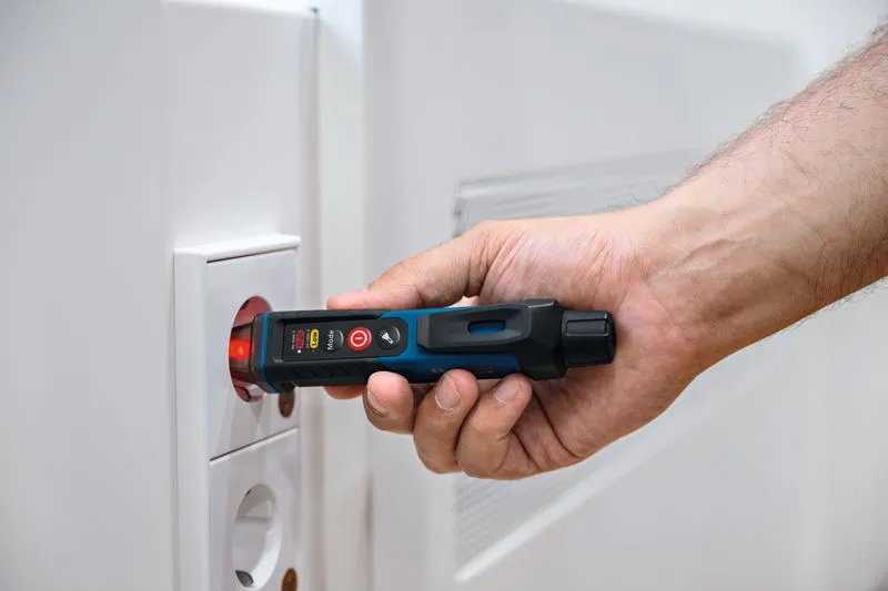 한 사람이 전기 소켓 근처에서 비접촉 전압 테스터를 사용하고 있습니다.