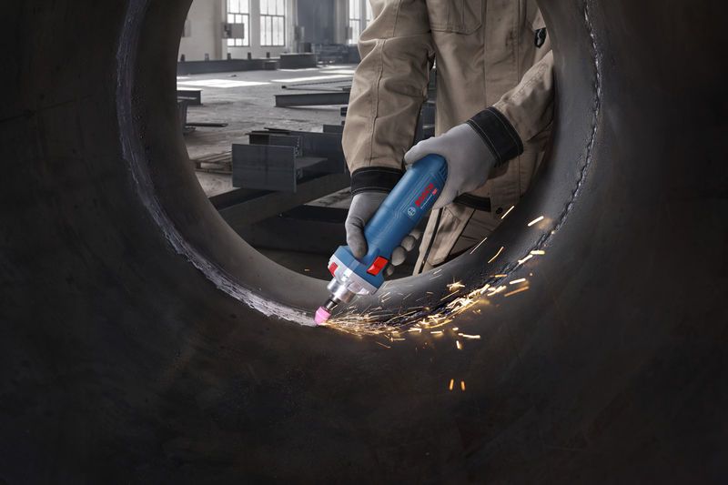 GGS 30 S 안전장비를 착용한 사람이 직선형 그라인더를 이용해 큰 금속 파이프의 내부를 갈고 있습니다.