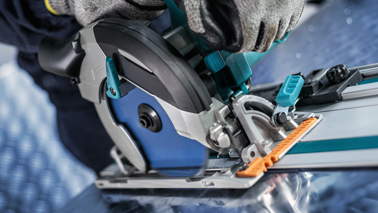 안전 장비를 착용한 사람이 가이드 레일에서 원형 톱을 조작하고 있습니다.