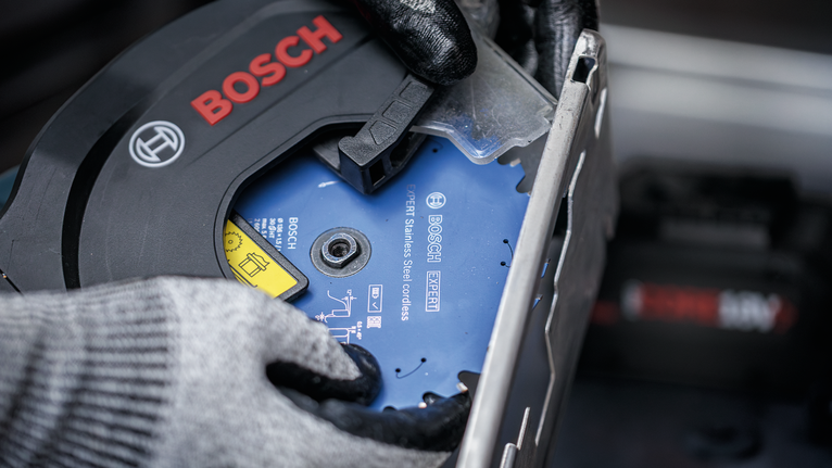 안전장비를 착용한 사람이 원형 톱날을 설치하고 있습니다.