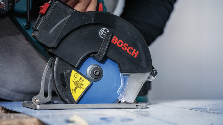 안전장비를 착용한 사람이 원형 톱으로 나무를 자릅니다.